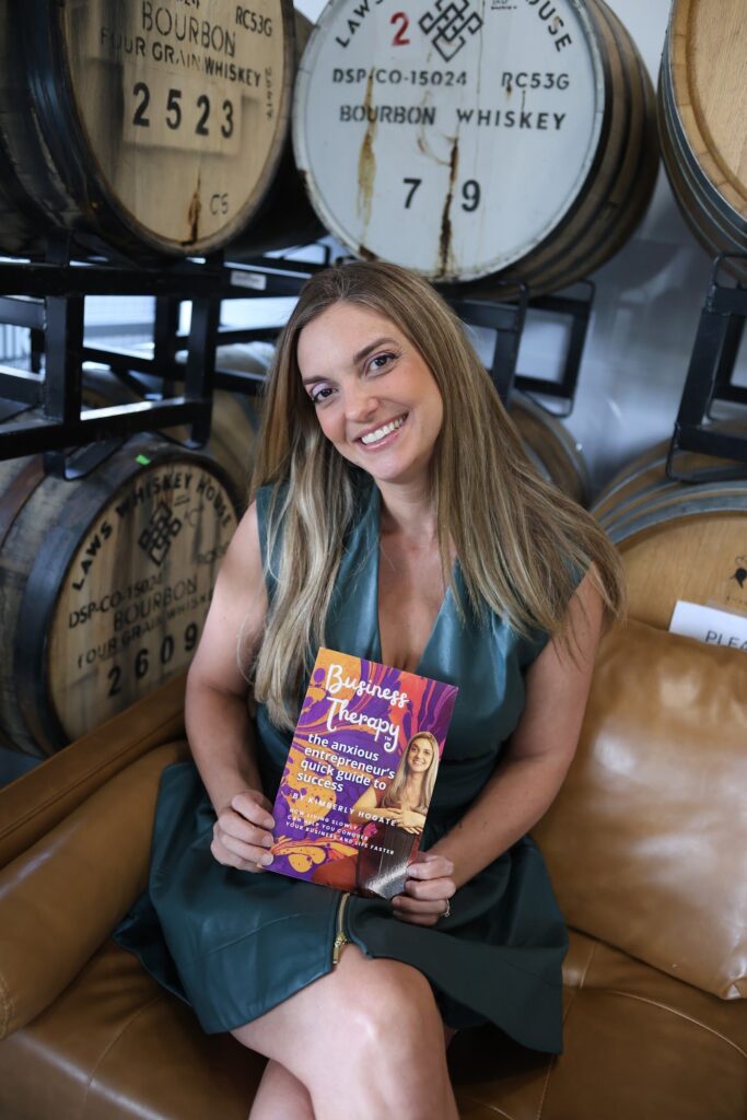 Author Kimberly Hogate holding a copy of Business Therapy: The Anxious Entrepreneur’s Quick Guide to Success